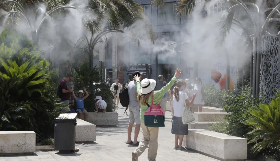 epa12204409 Tourists cool off under a cloud of mist at the Plaza de la Reina during a heat wave in Valencia, Spain, 29 June 2025. Spain is undergoing its first summer heat wave due to a broad anticyclone originating from the interior of the African continent which is expected to last until 01 July, according to the State Meteorological Agency (AEMET). EPA/MANUEL BRUQUE