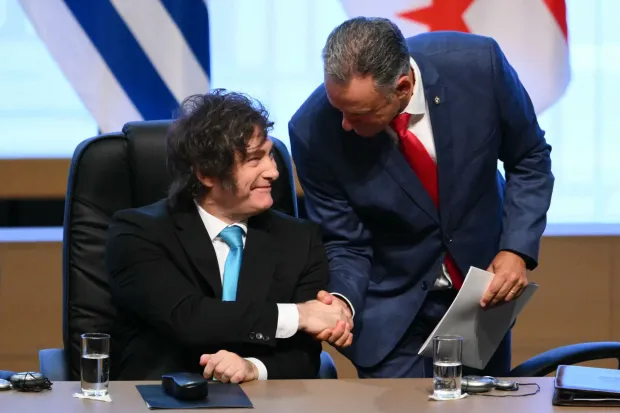 Argentina's President Javier Milei (L) and Uruguay's President Yamandu Orsi shake hands during the signing ceremony of the trade agreement between the European Union and Mercosur, at the Gran Teatro Jose Asuncion Flores of Paraguay's Central Bank in Asuncion on January 17, 2026. The South American bloc Mercosur and the European Union on January 17 signed a major trade deal that has been 25 years in the making. (Photo by Luis ROBAYO/AFP)