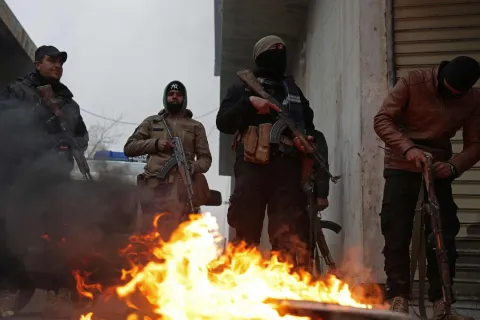 Syrian army personnel stand guard next to a burning tyre along a street in Tabqa, in Raqa province, on the southwestern banks of the Euphrates on January 18, 2026. Kurdish-led forces withdrew on January 18 from Syria's largest oil field, a conflict monitor said, as government troops extended their grip over swathes of territory in the country's north and east. Government troops drove Kurdish forces from two Aleppo neighbourhoods following clashes last week, and on January 17 announced they had captured an area east of the city, as well as Tabqa. (Photo by Bakr ALkasem/AFP)
