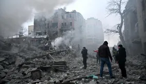 Local residents stand next to damaged residential buildings following a Russian air strike in Kharkiv on January 2, 2026, amid the Russian invasion of Ukraine. (Photo by SERGEY BOBOK/AFP)