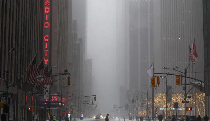A man walks across Sixth Avenue as snow falls in the Manhattan borough of New York City on January 25, 2026. A massive winter storm on January 24 dumped snow and freezing rain from New Mexico to North Carolina as it swept across the United States towards the northeast, threatening tens of millions of Americans with blackouts, transportation chaos and bone-chilling cold. After battering the country's southwest and central areas, the storm system began to hit the heavily populated mid-Atlantic and northeastern states as a frigid air mass settled in across the nation. (Photo by CHARLY TRIBALLEAU/AFP)