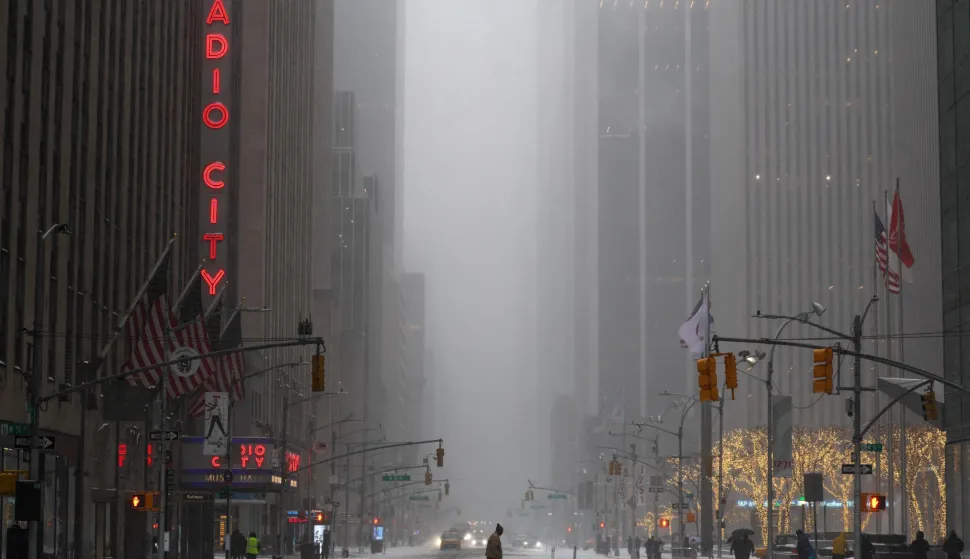 A man walks across Sixth Avenue as snow falls in the Manhattan borough of New York City on January 25, 2026. A massive winter storm on January 24 dumped snow and freezing rain from New Mexico to North Carolina as it swept across the United States towards the northeast, threatening tens of millions of Americans with blackouts, transportation chaos and bone-chilling cold. After battering the country's southwest and central areas, the storm system began to hit the heavily populated mid-Atlantic and northeastern states as a frigid air mass settled in across the nation. (Photo by CHARLY TRIBALLEAU/AFP)