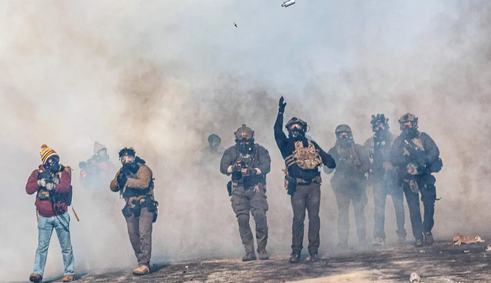 TOPSHOT - A federal agent lobs a teargas canister towards protesters as agents advance through clouds of tear gas during clashes following the fatal shooting of a protester earlier in the day, on January 24, 2026 in Minneapolis, Minnesota. Federal immigration agents shot dead a man in Minneapolis on Saturday, officials said -- the second fatal shooting of a civilian in the city, sparking fresh protests and outrage from state officials. The death came less than three weeks after US citizen Renee Good was shot and killed by an Immigration and Customs Enforcement officer involved in sweeps to round up undocumented migrants. (Photo by Kerem YUCEL/AFP)