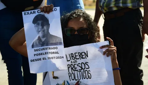 A woman shows signs during a demonstration to demand the freedom of Venezuelan political prisoners in front of Tocuyito prison in Tocuyito, near Valencia, Venezuela on January 20, 2026. Relatives of political prisoners reported on January 20, 2026, that some 200 people are in a state of "forced disappearance" in Venezuela and demanded proof of life from the prosecutor's office, amid a slow process of releases from prison under pressure from United States. (Photo by Jacinto OLIVEROS/AFP)