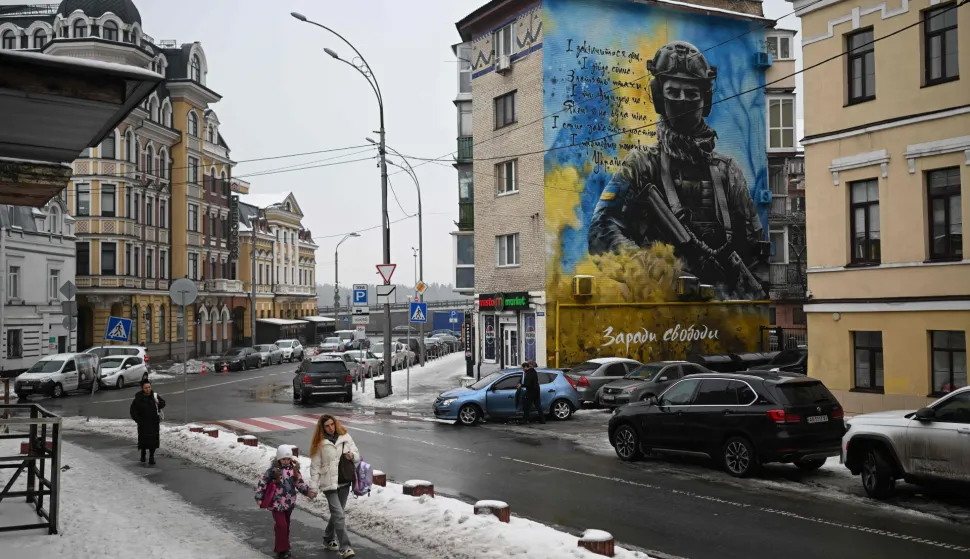 Pedestrians walk past a residential building with a patriotic mural depicting a Ukrainian soldier in Kyiv on January 28, 2026, amid the Russian invasion of Ukraine. (Photo by Sergei GAPON/AFP)