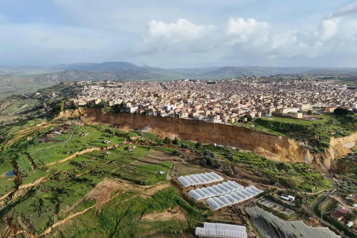TOPSHOT - This aerial view shows the giant landslide in the city of Niscemi, Sicily, on January 26, 2026. More than 1,000 people were evacuated in Sicily after a four-kilometre (2.5-mile) section of cliff crumbled during a storm, leaving houses perched perilously on the edge, authorities said on January 26, 2026. Land was continuing to give way due to rain that has soaked the area in recent days, said the mayor of the southern hill town of Niscemi. (Photo by Rosario CAUCHI/ANSA/AFP)/Italy OUT/----IMAGE RESTRICTED TO EDITORIAL USE - STRICTLY NO COMMERCIAL USE-----