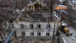This aerial photograph shows a damaged residential building as municipal workers clean debris next to it following a Russian overnight drone attack in Odesa on February 4, 2026, amid the Russian invasion of Ukraine. (Photo by Oleksandr GIMANOV/AFP)