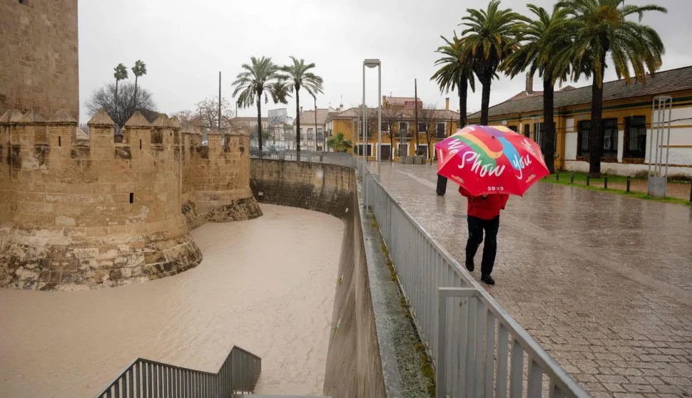 A man walks with his umbrella as Guadalquivir River's floodwaters cover an area in Cordoba on February 7, 2026. Spain and Portugal today braced for another storm, named Marta, heading for the Iberian peninsula, just days after the floods caused by Storm Leonardo proved fatal in both countries. (Photo by JORGE GUERRERO/AFP)