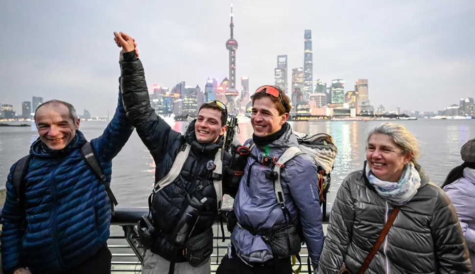 France's Loic Voisot (centre, R) and Benjamin Humblot (centre, L) celebrate with their families on the Bund promenade, marking the end of their remarkable walk from France to China, in Shanghai on February 7, 2026. Two French adventurers reached the end of an epic walk from France to Shanghai on February 7, after nearly a year and a half crossing 16 countries almost entirely on foot. (Photo by Jade GAO/AFP)