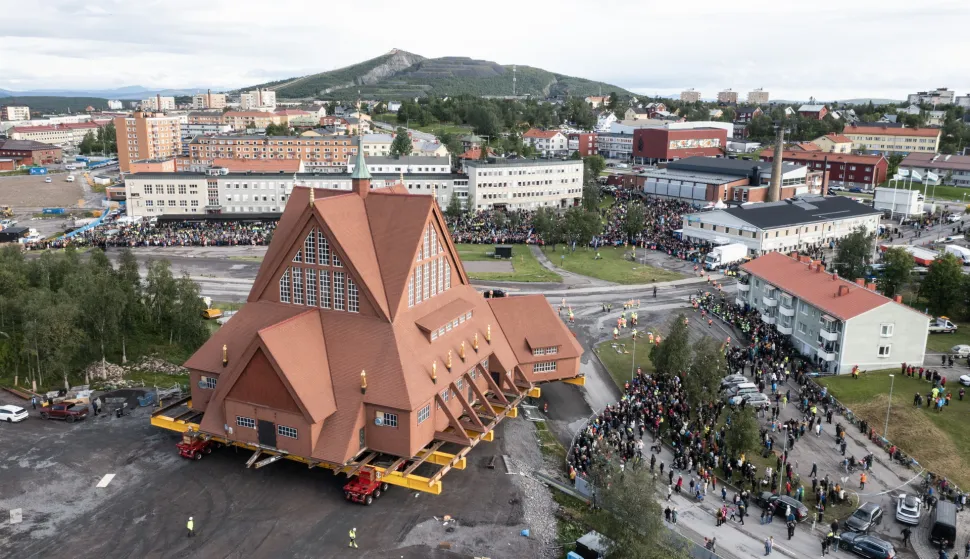 epa12309677 People watch as the Kiruna Church landmark is being moved on a specially designed trolley with 224 wheels at a speed of half a kilometer per hour in Kiruna, northern Sweden, 19 August 2025. The 40-meter-wide, 672,000-kilo wooden church has been placed on a wheeled trailer for its five-kilometre relocation to Kiruna's new town center on 19 and 20 August, due to the expansion of the iron ore mine. EPA/Fredrik Sandberg SWEDEN OUT