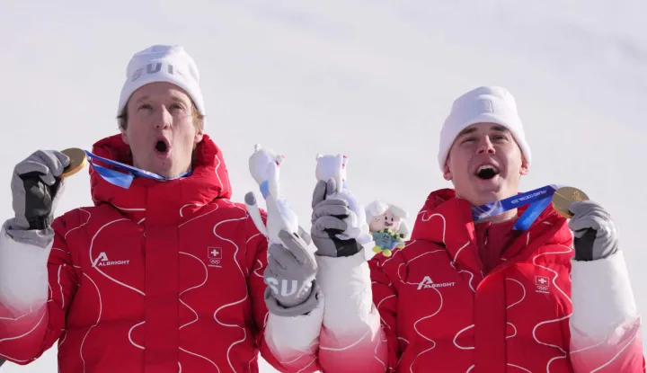 Gold medallists Switzerland's Tanguy Nef (L) and Switzerland's Franjo von Allmen celebrate on the podium of the men's team combined alpine skiing event during the Milano Cortina 2026 Winter Olympic Games at the Stelvio Ski Centre in Bormio (Valtellina) on February 9, 2026. (Photo by Dimitar DILKOFF/AFP)