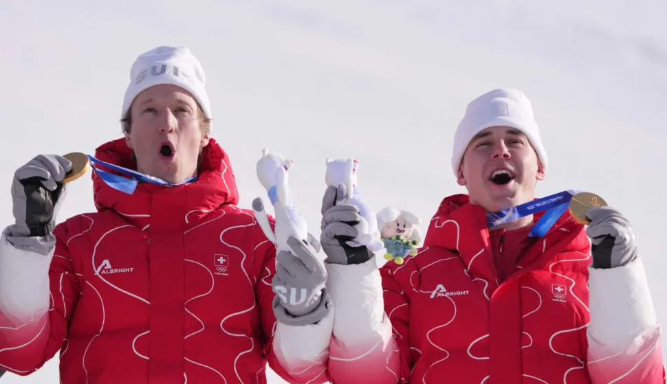 Gold medallists Switzerland's Tanguy Nef (L) and Switzerland's Franjo von Allmen celebrate on the podium of the men's team combined alpine skiing event during the Milano Cortina 2026 Winter Olympic Games at the Stelvio Ski Centre in Bormio (Valtellina) on February 9, 2026. (Photo by Dimitar DILKOFF/AFP)