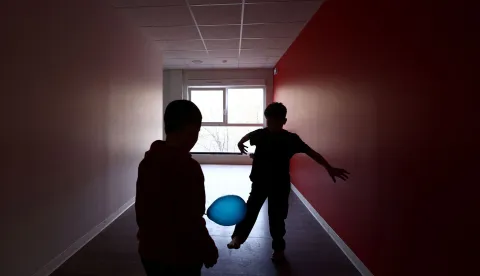 Two boys play in a corridor at an empty school near the Blandan's park in Lyon, south-eastern France, on January 10, 2026 where homeless families are being housed by a collective. Classrooms turned into dormitories and a cafeteria: more than 80 children without a roof over their heads are occupying an empty school in Lyon with their parents, in an operation of a "highly exceptional" scale carried out on January 9, 2026 evening by the collective "Jamais Sans Toit" (JST) due to the lack of housing solutions. (Photo by Alex MARTIN/AFP)