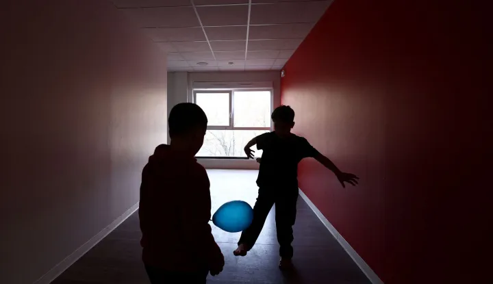 Two boys play in a corridor at an empty school near the Blandan's park in Lyon, south-eastern France, on January 10, 2026 where homeless families are being housed by a collective. Classrooms turned into dormitories and a cafeteria: more than 80 children without a roof over their heads are occupying an empty school in Lyon with their parents, in an operation of a "highly exceptional" scale carried out on January 9, 2026 evening by the collective "Jamais Sans Toit" (JST) due to the lack of housing solutions. (Photo by Alex MARTIN/AFP)