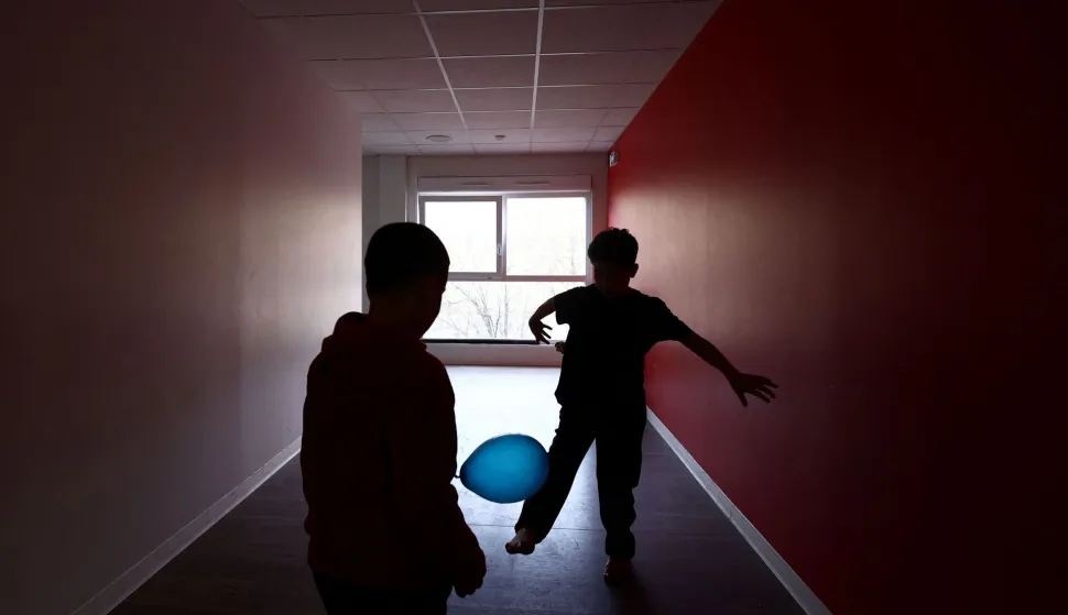 Two boys play in a corridor at an empty school near the Blandan's park in Lyon, south-eastern France, on January 10, 2026 where homeless families are being housed by a collective. Classrooms turned into dormitories and a cafeteria: more than 80 children without a roof over their heads are occupying an empty school in Lyon with their parents, in an operation of a "highly exceptional" scale carried out on January 9, 2026 evening by the collective "Jamais Sans Toit" (JST) due to the lack of housing solutions. (Photo by Alex MARTIN/AFP)