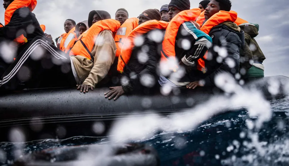 (FILES) Migrants onboard a crowded rubber boat wait as crew members of the ?Ocean Viking? rescue ship carry out a rescue operation in the search-and-rescue zone off the international waters of Libya, on January 16, 2026. Nearly six months after coming under fire off the coast of Libya, the "Ocean Viking", an ambulance ship chartered by SOS Mediterranee, has returned to sea for the first time in recent weeks, rescuing more than 120 migrants in a sometimes tense context. (Photo by Sameer Al-DOUMY/AFP)