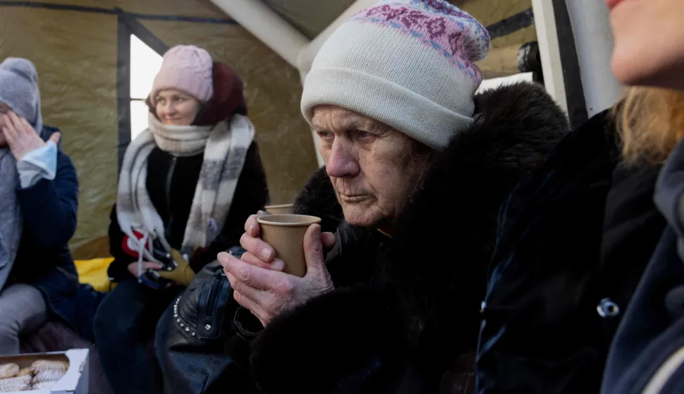 Local residents warm themselves in a tent next to a dry sauna organized by Artemiy and his wife Marina set up for those whose homes are without electricity or heating following Russian missile and drone attacks on Ukrainian energy infrastructure, in a residential neighborhood of Kyiv on February 10, 2026, amid the Russian invasion of Ukraine. (Photo by Tetiana DZHAFAROVA/AFP)