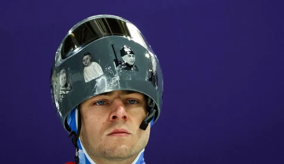 In this file photo taken on February 9, 2026 Ukraine's Vladyslav Heraskevych wears a helmet with pictures of Ukrainian sportsmen and women, victims of his country's war with Russia, prior to taking part in the skeleton men's training session at Cortina Sliding Centre during the Milano Cortina 2026 Winter Olympic Games in Cortina d'Ampezzo. Ukrainian skeleton racer Vladyslav Heraskevych was disqualified from the Winter Olympics on February 12, 2026 after refusing to back down over his banned helmet, which depicts victims of his country's war with Russia. In a statement, the International Olympic Committee said Heraskevych is "not allowed to participate at Milano-Cortina 2026 after refusing to adhere to the IOC athlete expression guidelines". (Photo by FRANCK FIFE/AFP)