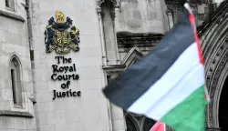 A Palestinian flag is flown by a protestor outside The Royal Courts of Justice, Britain's High Court, in London on February 13, 2026. Palestine Action co-founder Huda Ammori is set Friday to learn the outcome of his challenge against the UK Government's ban on the group, which came into force in July 2025, after pro-Palestine activists protesting the war in Gaza, broke into a UK air force base and caused an estimated ?7 million (.3 million) of damage. (Photo by Ben STANSALL/AFP)