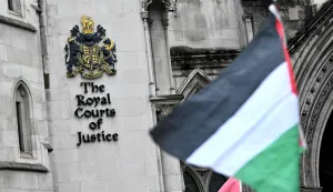 A Palestinian flag is flown by a protestor outside The Royal Courts of Justice, Britain's High Court, in London on February 13, 2026. Palestine Action co-founder Huda Ammori is set Friday to learn the outcome of his challenge against the UK Government's ban on the group, which came into force in July 2025, after pro-Palestine activists protesting the war in Gaza, broke into a UK air force base and caused an estimated ?7 million (.3 million) of damage. (Photo by Ben STANSALL/AFP)