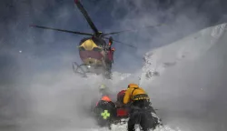 A Securite Civile helicopter (emergency management) lands as rescuers and members of the CRS Alpes Grenoble mountain rescue team prepare to board and evacuate an avalanche victim in an off-piste area of the Ecrins massif, French Alps during an avalanche emergency reponse rescue mission on January 29, 2026. (Photo by JEFF PACHOUD/AFP)