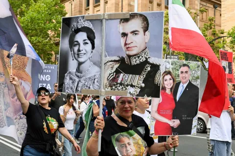 A member of the Iranian community carries a poster of last Shah of Iran Mohammad Reza Pahlavi during a rally in Sydney on February 14, 2026, calling for stronger international action and urging the United States to intervene against the current Iranian regime. (Photo by Saeed KHAN/AFP)