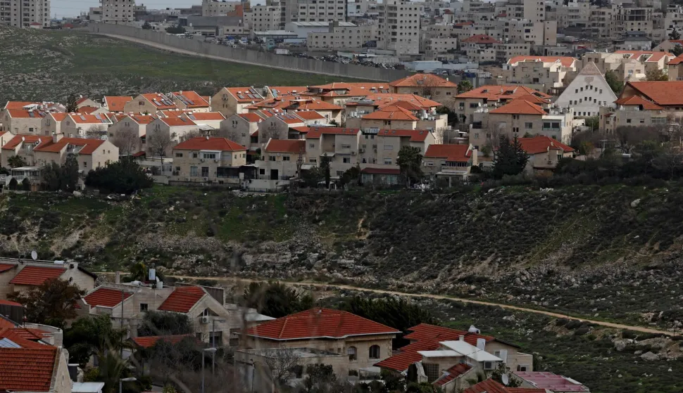Israel's controversial barrier is pictured separating the Israeli settlement of Pisgat Zeev (foreground), built in a suburb of the predominantly-Arab and Israeli-annexed East Jerusalem, and the Palestinian village of Anata (background) on February 11, 2026. (Photo by AHMAD GHARABLI/AFP)