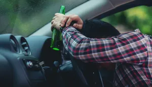 Hansome man holding beer bottle while driving a caralkohol voznja promet cesta pijan