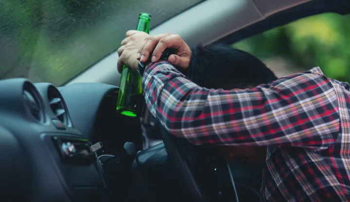 Hansome man holding beer bottle while driving a caralkohol voznja promet cesta pijan