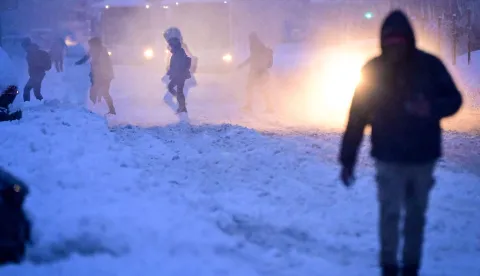 People walk on a boulevard during heavy snowfall in Bucharest, Romania, on February 18, 2026. Romanian authorities issued a Code Orange warning for several counties, as heavy snowfall and blizzard conditions disrupted transport and forced schools to close across the country's southern and eastern regions. (Photo by Daniel MIHAILESCU/AFP)