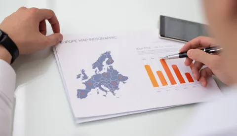 Close-up of male hands working with Europe sales statistic report. Caucasian businessman sitting at table and examining financial paper. Marketing concept