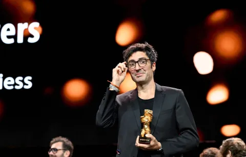 German film director ?lker Catak holds the Golden Bear for Best Film he was given for his movie "Gelbe Briefe (Yellow Letters)" during the Award Ceremony of the 76th Berlinale, Europe's first major film festival of the year, in Berlin on February 21, 2026. The 76th Berlin Film Festival draws to a close after 10 days, with 22 films in competition. (Photo by RALF HIRSCHBERGER/AFP)