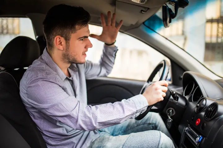 Side view of angry man in suit driving car