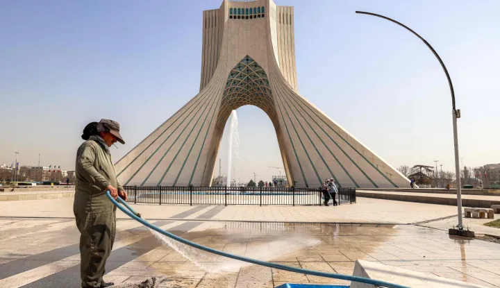A municipal worker uses a hose to clean an area of Azadi (Freedom) Square near the landmark Azadi Tower in Tehran on February 23, 2026. The 45-metre-tall marble-clad Azadi Tower, formerly known as Shahyad Tower (Shah's Memorial Tower'), was commissioned by Mohammad Reza Pahlavi, the last Shah of Iran, to mark the 2,500-year celebration of the Persian Empire, and completed in 1971. It was erected at the westernmost entrance to the city of Tehran. (Photo by ATTA KENARE/AFP)