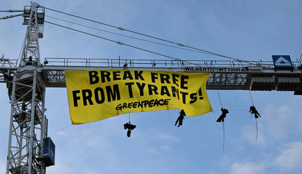 Greenpeace activists hang on a crane on which they have fixed a banner reading "Break Free From Tyrants!" near the Hotel Bayerischer Hof, venue of the Munich Security Conference (MSC) in Munich, southern Germany on February 13, 2026. Heads of state and government as well as foreign and defence ministers from all over the world are expected to attend the security policy talks from February 13 to 15, 2026. (Photo by THOMAS KIENZLE/AFP)