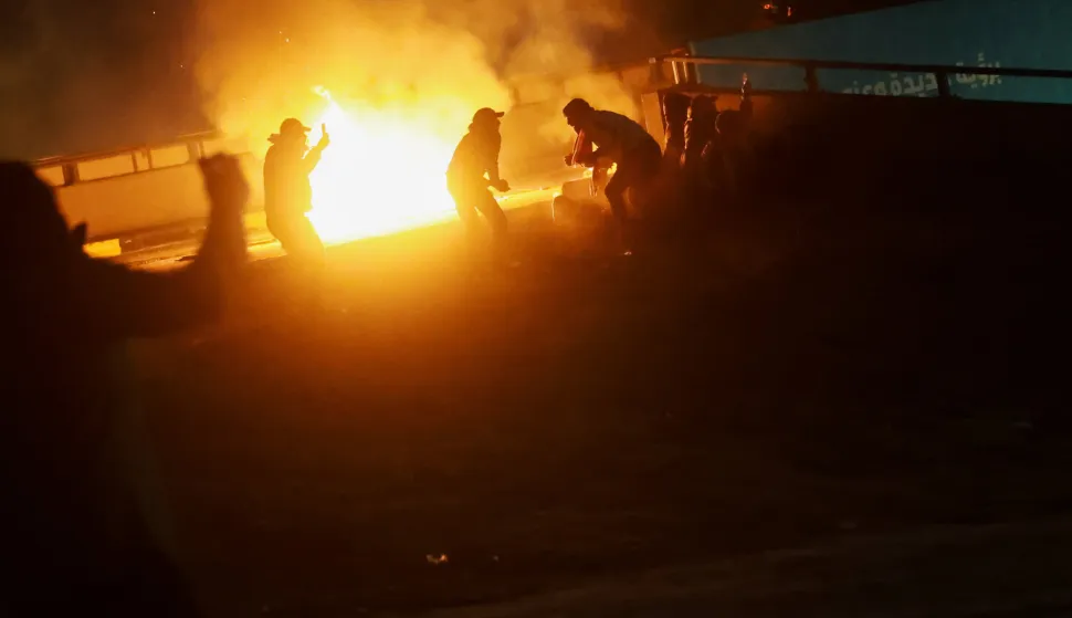 People are silhouetted against a fire as supporters of Iraqi Shi'ite armed groups attempt to move toward the U.S. embassy located in Baghdad's Green Zone following the Israel and U.S. strikes on Iran and the killing of Iran's Supreme Leader Ali Khamenei, in Baghdad, Iraq, March 1, 2026. REUTERS/Ahmed Saad Photo: AHMED SAAD/REUTERS