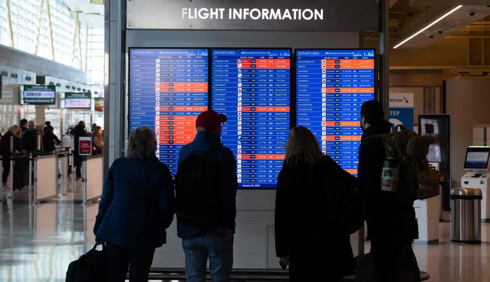 Travelers look at a flight status board as flights are delayed and cancelled following a significant winter storm at Ronald Reagan Washington National Airport in Arlington, Virginia, January 26, 2026. Millions of Americans were facing dangerously cold temperatures in the wake of a massive winter storm that whipped snow and ice across the country, knocking out power and paralyzing transportation. A frigid, potentially life-threatening Arctic air mass threatened to delay clean-up as municipalities from New Mexico to Maine tried to dig out following the storm, which dropped a vicious cocktail of heavy snow and wind along with freezing rain and sleet. (Photo by SAUL LOEB/AFP)