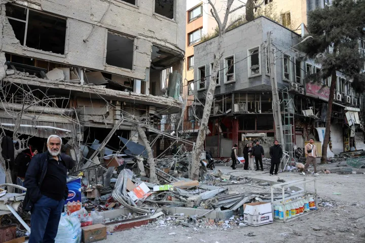 Residents stand on a street beside damaged residential buildings near Niloufar square in Tehran during the ongoing joint US-Israeli military campaign on Iran on March 2, 2026. The United States and Israel launched strikes against Iran on February 28, killing Iran's supreme leader and top military leaders, prompting authorities to retaliate with strikes on Israel and across the Gulf. (Photo by AFP)