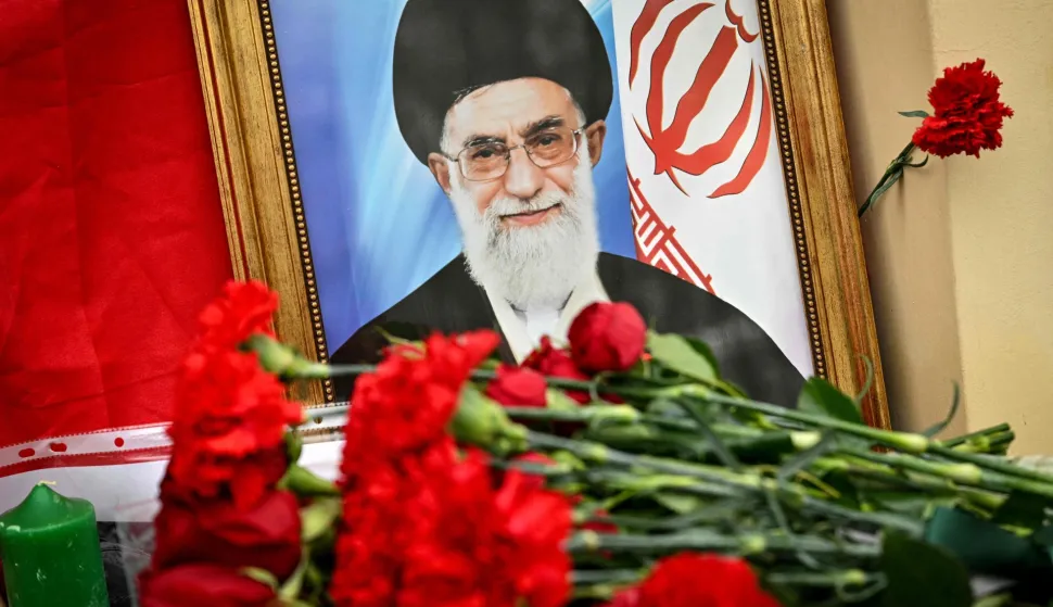 This photograph shows flowers laid at a makeshift altar with a portrait of late Iran's supreme leader Ayatollah Ali Khamenei and a flag of the Islamic Republic of Iran outside the Iranian Embassy in Russia, in Moscow on March 2, 2026. Russian President on March 1 slammed the United States and Israel's killing of Khamenei as a "cynical violation" of morality and law. Tehran has stood by as one of Russia's closest allies throughout Moscow's Ukraine offensive, and the Kremlin had earlier called for restraint in the run-up to the US-Israeli strikes on Iran. (Photo by HECTOR RETAMAL/AFP)
