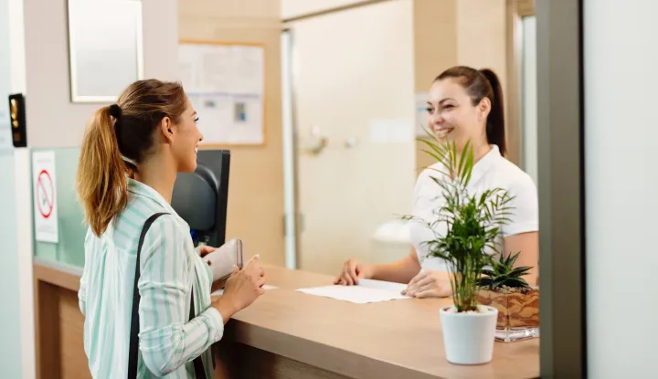 Young happy woman checking in health spa and communicating with a receptionist.banka &scaron;alter novacfreepik