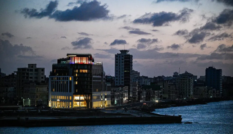 A hotel is illuminated among otherwise dark buildings during a blackout in Havana on March 4, 2026. (Photo by Adalberto ROQUE/AFP)