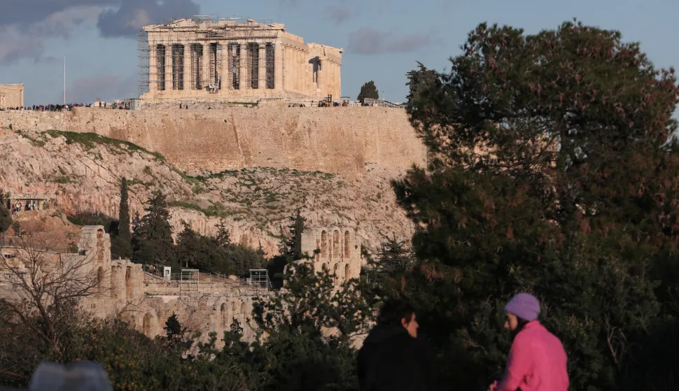 epa09663678 Two people sit on a wall overlooking the Temple of Athena Nike at the Acropolis in Athens, Greece, 02 January 2022. EPA/GEORGE VITSARAS