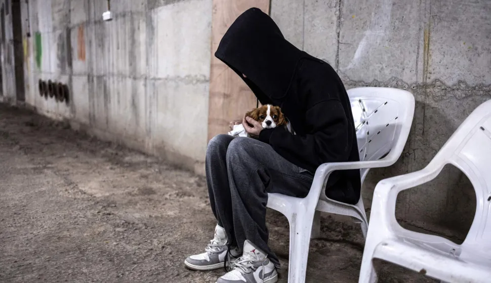 TOPSHOT - A man holds tight on his dog in an underground parking used as a bomb shelter during an alert in Tel Aviv on March 12, 2026. Lebanon's Hezbollah said it launched missiles at an Israeli military intelligence base in the suburbs of Tel Aviv early on March 12, the Iran-backed group's latest claim in a major operation against Israel it announced hours earlier. (Photo by OLYMPIA DE MAISMONT/AFP)/