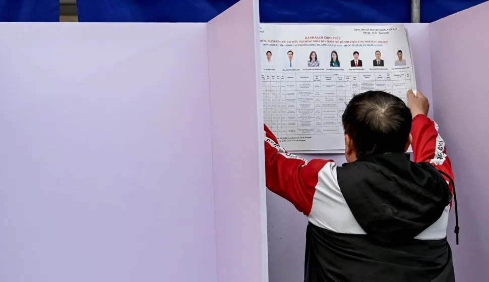 A man puts up voting information at a polling station for the upcoming National Assembly and local People's Council elections at a voting site in Hanoi on March 13, 2026. Vietnam goes to the polls on March 15 to elect members of the National Assembly, the country's top legislative body that serves mainly to ratify decisions by the ruling Communist Party. (Photo by Nhac NGUYEN/AFP)