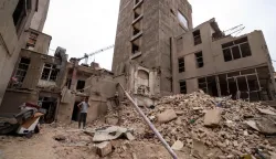An Iranian man speaks on his mobile phone as he stands on the debris in front of destroyed buildings following a military strike on the Iranian capital Tehran on March 15, 2026. Iran's Foreign Minister said in an interview published on March 15, that the war pitting his country against the United States and Israel will only end when Tehran can be certain it will not be restarted. On February 28, Israel and the United States launched strikes on Iran, killing its supreme leader Ayatollah and triggering a war that spread across the Middle East. (Photo by Atta KENARE/AFP)/