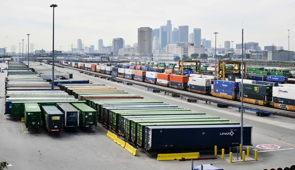 The downtown Los Angeles skyline is seen behind shipping containers and container trucks at the LATC-Union Pacific Los Angeles Transportation Center rail yard on February 24, 2026 in Los Angeles, California. Fresh US tariffs on imported goods came into effect Tuesday, as President Donald Trump moved to rebuild his trade agenda after the Supreme Court ruled against a swath of his global duties. The new tariffs, set at 10 percent initially, were justified as a means of dealing with "large and serious United States balance-of-payments deficits," according to a White House order on Friday. (Photo by Frederic J. BROWN/AFP)