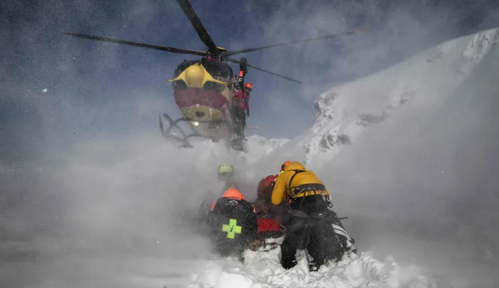 A Securite Civile helicopter (emergency management) lands as rescuers and members of the CRS Alpes Grenoble mountain rescue team prepare to board and evacuate an avalanche victim in an off-piste area of the Ecrins massif, French Alps during an avalanche emergency reponse rescue mission on January 29, 2026. (Photo by JEFF PACHOUD/AFP)