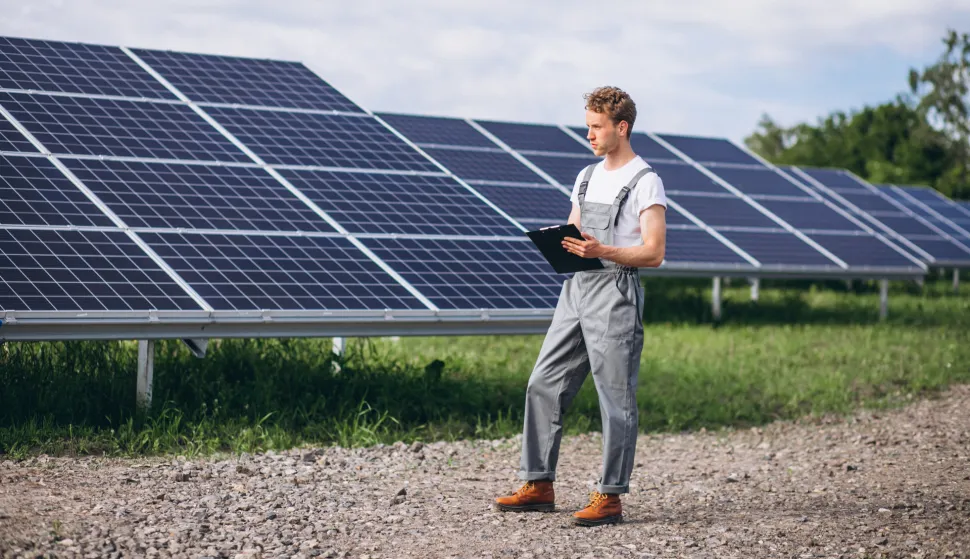 Man worker in the firld by the solar panels