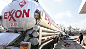 FILE - In this Jan. 30, 2009 file photo, an Exxon tanker truck operated by Corey Moorer, right, of Clinton, Md., makes a refueling stop at an Exxon station in Arlington, Va. Exxon Mobil said Monday, Feb. 1, 2010, its fourth-quarter earnings tumbled 23 percent as higher oil prices squeezed profit margins in its refining business.(AP Photo/J. Scott Applewhite, file)