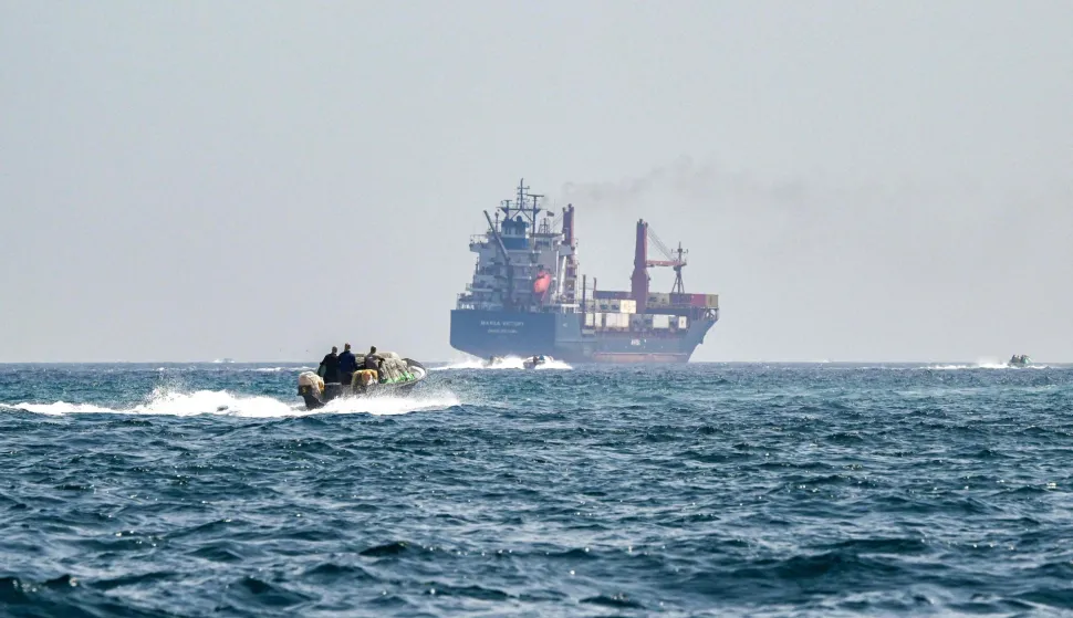 (FILES) A boat approaches the St Kitt's and Nevis-flagged container ship Marsa Victory while crusing in the waters of the Strait of Hormuz off the coast of Khasab in Oman?s northern Musandam peninsula on June 25, 2025. (Photo by Giuseppe CACACE/AFP)